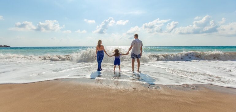 family of 3 standing on beach