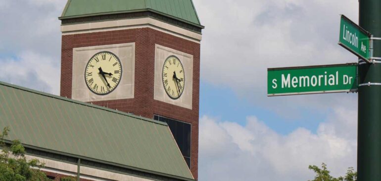 Lancaster's iconic clock tower with street signs under a clear blue sky